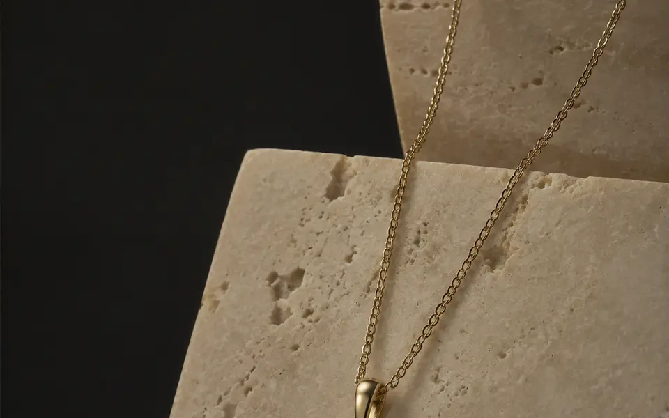 Emerald cut diamond pendant in yellow gold on travertine