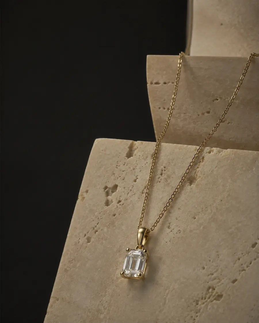 Emerald cut diamond pendant on warm ivory stone